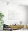 A modern living room with a wooden sideboard, a chair with a blanket, and a large abstract painting on the wall. Podgląd zdjęcia produktu