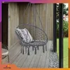 A hanging chair on a wooden deck next to a house. Voir les images du produit