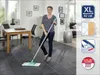A woman is cleaning a floor with a mop in a modern living room. Produktbild-Vorschau