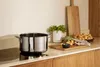 A stainless steel pot on a stovetop with potatoes and other kitchen items in the background. Produktbild-Vorschau