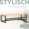 A wooden shelf with a black metal frame, equipped with hooks and hangers, mounted on a white wall. Produktbild-Vorschau