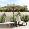 Two lounge chairs and a patio umbrella are set up on a paved patio area, surrounded by lush green bushes and trees, with a wooden fence in the background. Náhľad obrázku produktu