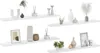 Four white shelves with various decorative items on them. Voir les images du produit