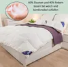 A bed with a white duvet and purple throw blanket, with a close-up of feathers in a hand in the upper left corner. Produktbild-Vorschau