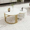 A white marble-patterned round coffee table with a gold base is next to a cylindrical white side table with two drawers and gold accents. The tables are on a patterned rug in a living room setting. Náhled obrázku produktu