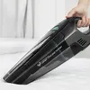 A hand holding a black handheld vacuum cleaner on a white surface. Podgląd zdjęcia produktu