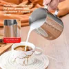 A hand is pouring milk from a metal pitcher into a coffee cup, demonstrating latte art. Anteprima dell’immagine prodotto