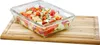 A glass food container filled with chopped vegetables sits on a wooden cutting board. Anteprima dell’immagine prodotto