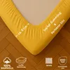 A close-up of a yellow fitted sheet corner on a wooden floor, highlighting its elastic edge and fabric texture. Produktbild-Vorschau