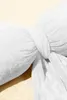 A close-up of a white fabric bow tied around a pillow or cushion. Produktbild-Vorschau