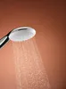 A close-up shot of a shower head with water spraying from it against a plain brown background. Produktbild-Vorschau