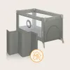 A gray and beige travel crib with a foldable playpen accessory next to it, and a cleaning icon overlay. Produktbild-Vorschau