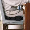 A person sitting on a chair with a cushion, next to a wooden cabinet. Podgląd zdjęcia produktu