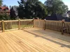 A wooden deck with a railing, overlooking houses and trees. Produktbild-Vorschau