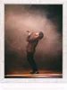 A man singing into a microphone on a stage with smoke and lighting. Produktbild-Vorschau