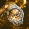A close-up shot of a transparent G-Shock watch with a gold dial, set against a shimmering gold background. Voir les images du produit