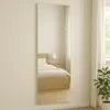 A full-length mirror is shown leaning against a wall in a bedroom, reflecting a bed and a nightstand with a lamp. Produktbild-Vorschau