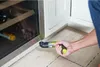 A person is using a power screwdriver to adjust a wine cooler door hinge. Voir les images du produit