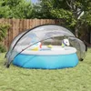 An inflatable pool with a transparent dome cover, set up on a grassy lawn in a backyard. Voir les images du produit