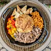 A cast iron skillet filled with food, placed on a grill. Produktbild-Vorschau