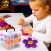 A young girl is engaged in a crafting activity, using felt materials to create a flower. Produktbild-Vorschau