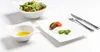 A table setting with a salad, a small bowl of dressing, and a plate with mozzarella, tomatoes, and basil, along with cutlery. Podgląd zdjęcia produktu