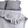 A close-up view of a light gray duvet cover with ruffles on a bed. Produktbild-Vorschau