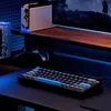 A gaming setup with a keyboard, controller, and gaming console on a desk with ambient blue lighting. Produktbild-Vorschau