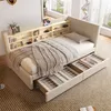 A bedroom scene featuring a beige sofa bed with open storage drawers, a blanket, and shelves with decorative items. Produktbild-Vorschau