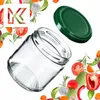 A clear glass jar with a green lid, surrounded by various fresh vegetables and herbs. Podgląd zdjęcia produktu