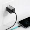 A black USB-C charger plugged into a white wall socket, connected by a black cable to a smartphone which is also connected by a blue and black cable. Produktbild-Vorschau