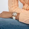 A person wearing a peach sweater and blue jeans, showing off a white and rose gold watch on their wrist. Náhľad obrázku produktu