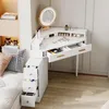 A white corner vanity desk with a lighted mirror and drawers, placed next to a bed. Produktbild-Vorschau