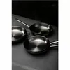 Three stainless steel frying pans are arranged on a dark gray surface with a dark, textured background. Produktbild-Vorschau