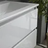 A close-up view of a white, glossy bathroom vanity with drawers, showing the sink basin and the front of the drawers. A plant is visible in the background. Anteprima dell’immagine prodotto