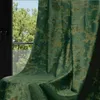 A green velvet curtain with a gold print is draped over a chair in front of a window with trees visible outside. Voir les images du produit