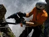 A climber is using a Bosch rotary hammer drill to drill into a rock face, with a waterfall in the background. Produktbild-Vorschau