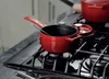 A red cast iron pot and lid are on a gas stove. Anteprima dell’immagine prodotto