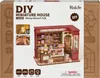 The image shows the packaging of a DIY miniature house kit, specifically a dessert shop model. The packaging displays the product name, brand, and a visual representation of the finished miniature house. Anteprima dell’immagine prodotto