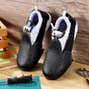 A pair of black and white safety overshoes with steel toes are placed on a wooden surface, with a screwdriver and a wrench nearby. Produktbild-Vorschau