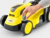 A hand is shown adjusting a part of a yellow lawnmower. Produktbild-Vorschau