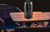 A black patio heater sits on a table next to chairs on a patio at night. Produktbild-Vorschau