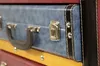 A close-up view of a stack of colorful suitcases, showing details of the handle, latch, and trim. Podgląd zdjęcia produktu
