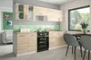 A modern kitchen setup with light brown cabinets, a black oven, and green hexagonal backsplash tiles.