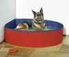 A German Shepherd dog is relaxing in a red and blue dog pool filled with water. Anteprima dell’immagine prodotto