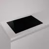 A black induction hob is shown on a light gray countertop. Voir les images du produit