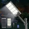 A solar street light and its components are displayed in a garden setting at dusk. Produktbild-Vorschau