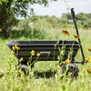 A black garden cart sits in a field of grass and wildflowers. Náhled obrázku produktu