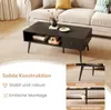 A black coffee table with storage is shown in a living room setting, with text overlays highlighting its features. Produktbild-Vorschau