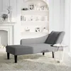 A grey chaise lounge is placed on a patterned rug in a room with a fireplace and shelves. Produktbild-Vorschau
